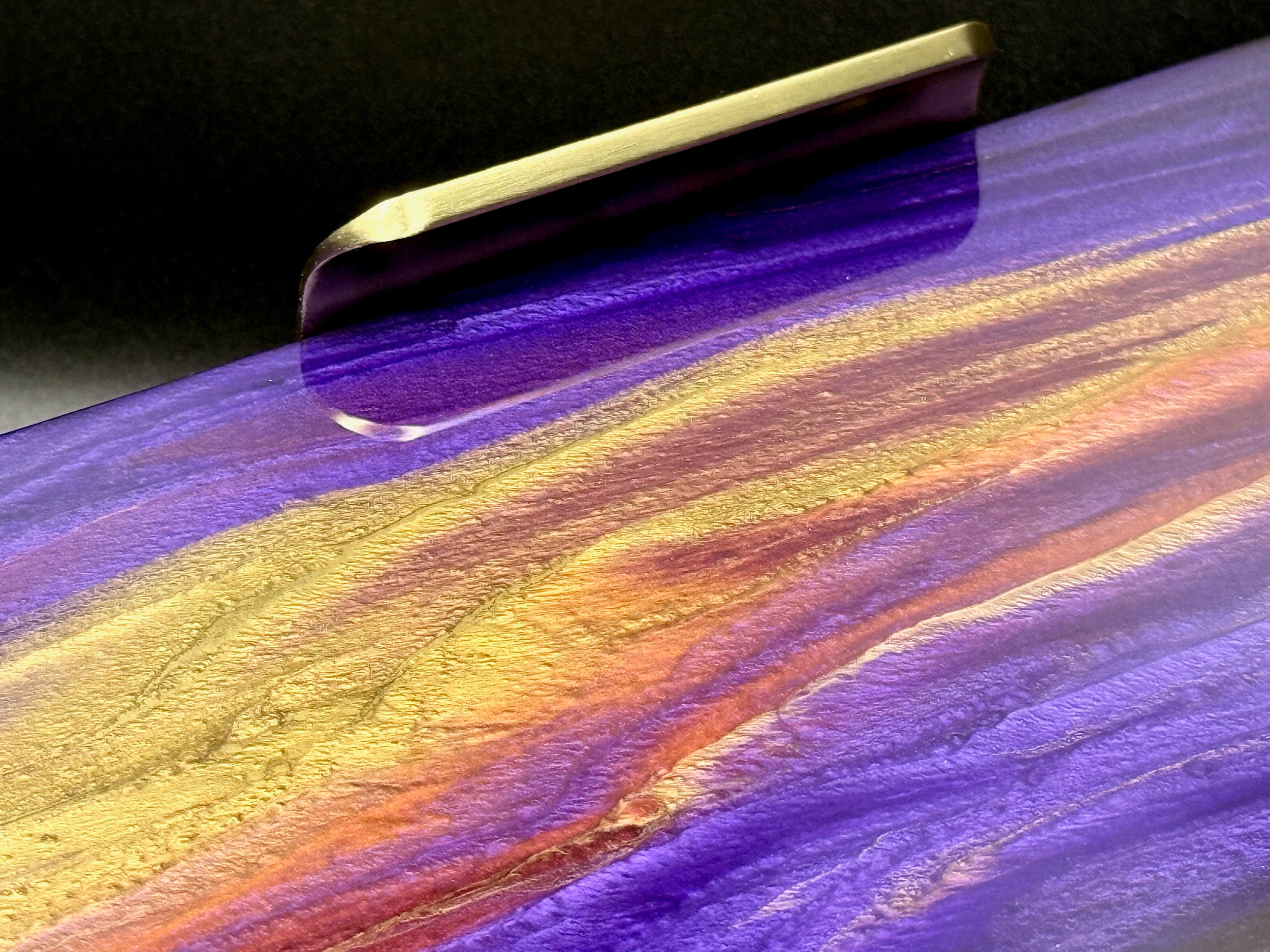 Colorful abstract painting with wavy patterns in purple, gold, and yellow on a dark background.