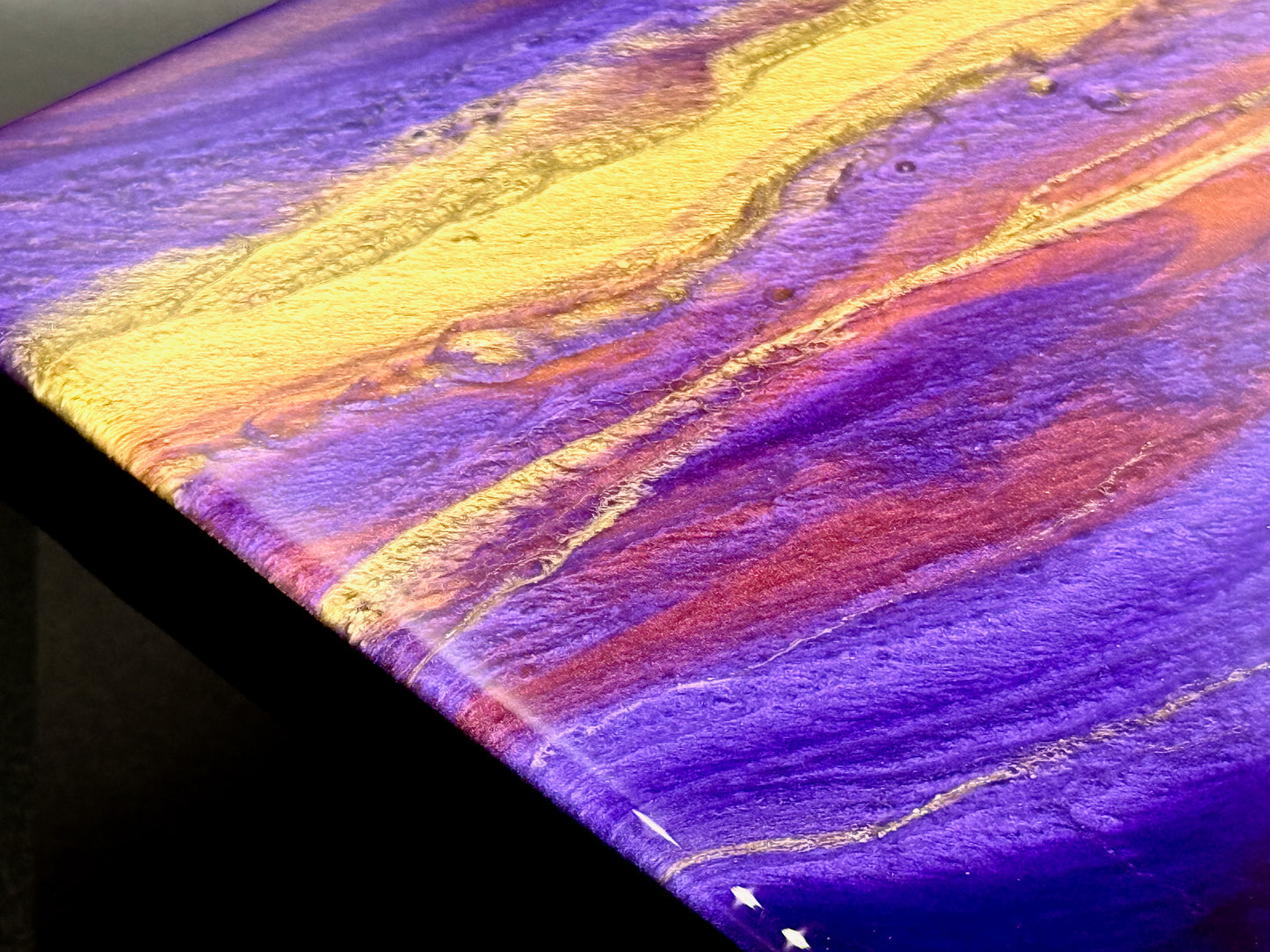 Colorful abstract painting with wavy patterns in purple, gold, and yellow on a dark background.