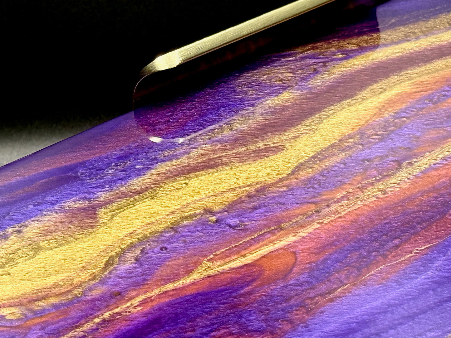 Colorful abstract painting with wavy patterns in purple, gold, and yellow on a dark background.